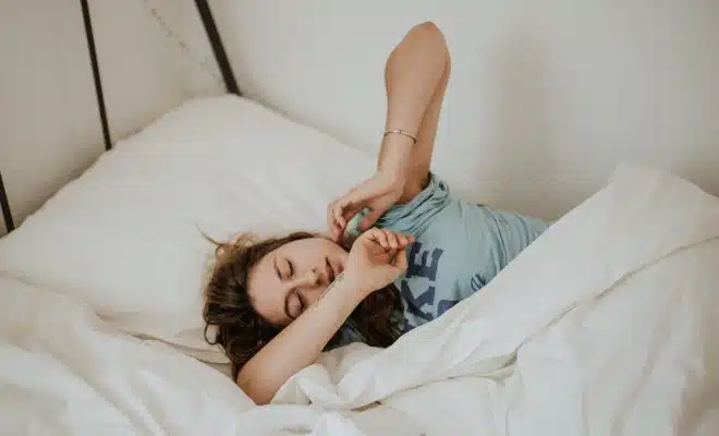 woman covered in white blanket sleeping on white bed comforter